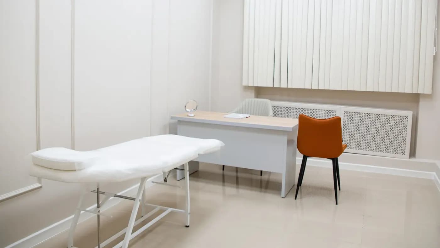 Muayene masası, çalışma masası ve danışan sandalyesi bulunan klinik odası